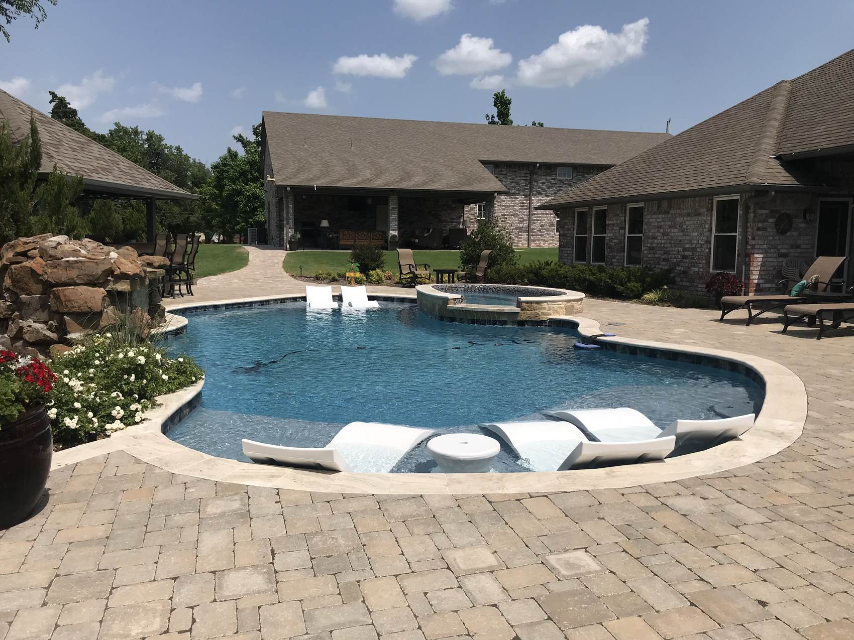 Custom backyard pool with in-water loungers and paver deck, Oklahoma