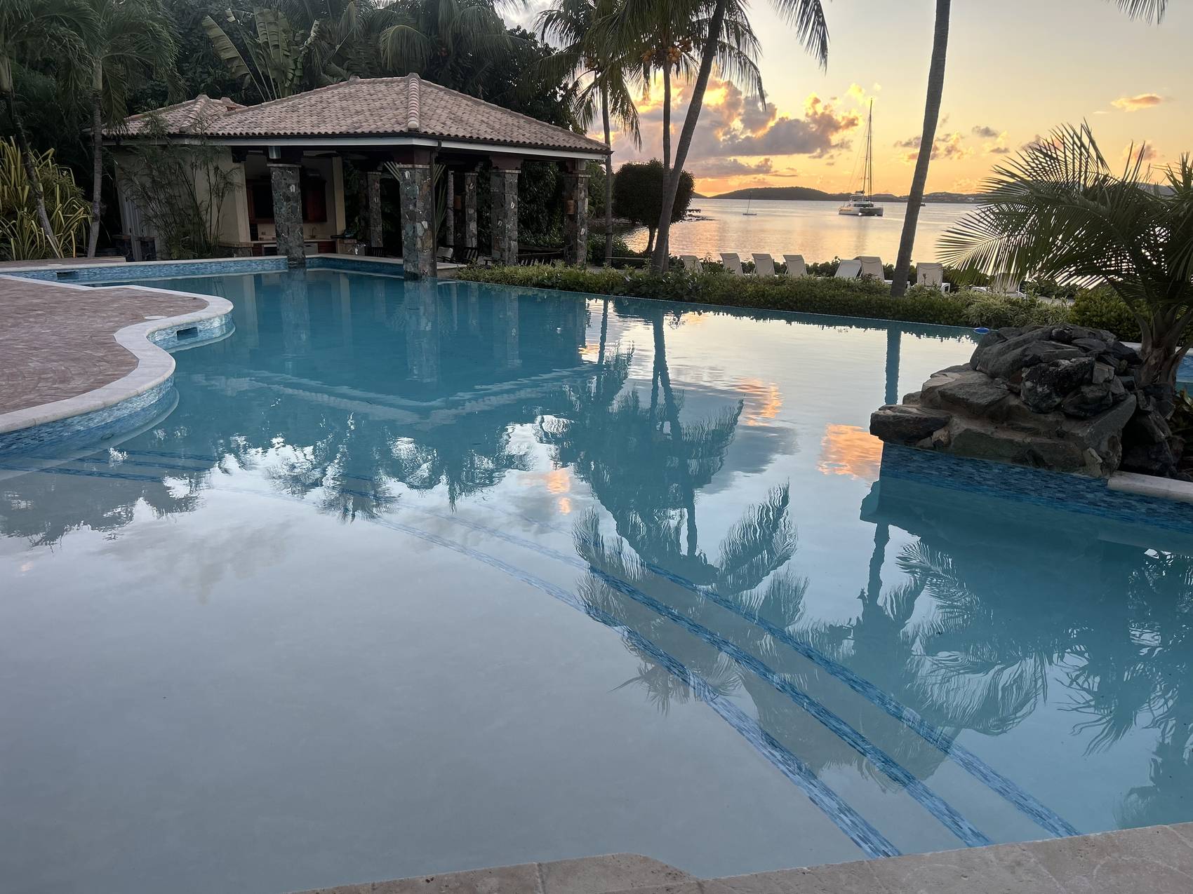 Resort-style pool at sunset with poolside pavilion and palms, St. John, USVI